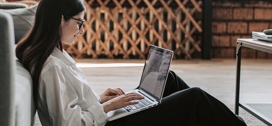 Young woman in living room on computer.